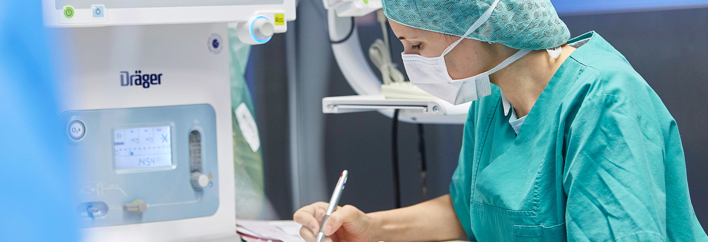 Eine Mitarbeiterin der Klinik für Unfallchirurgie, Orthopädie und Handchirurgie in Kaiserslautern in OP-Kleidung notiert etwas auf einem Blatt