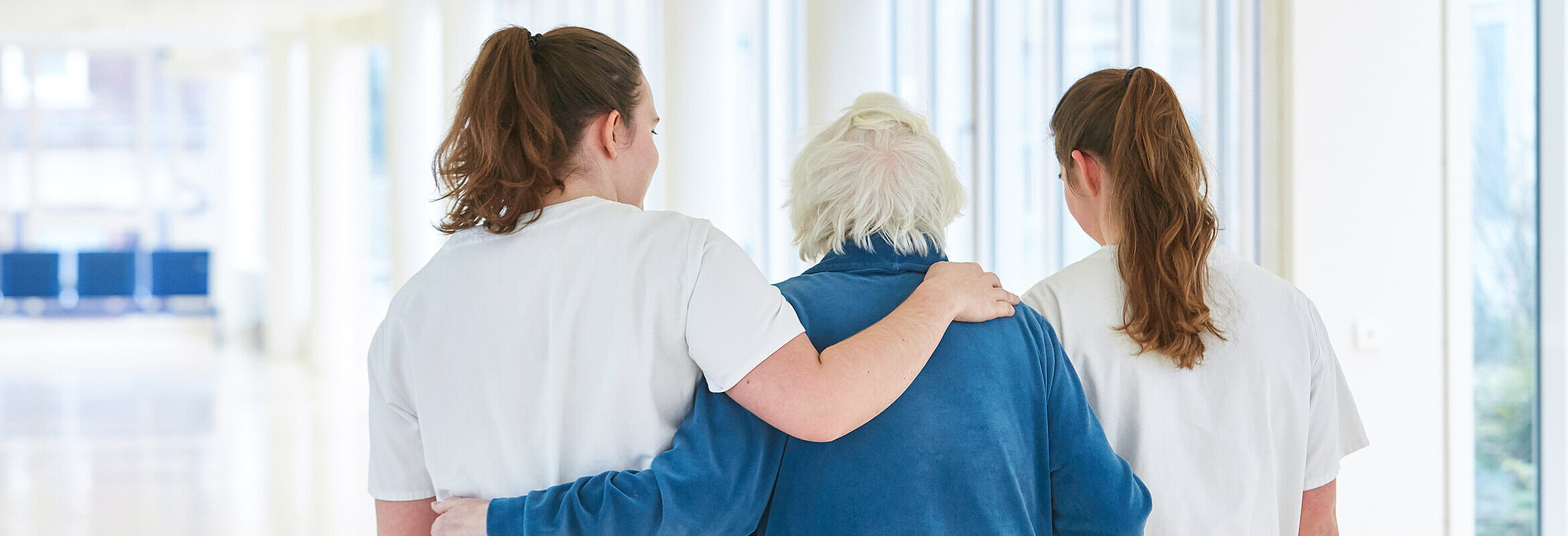 FSJ im Westpfalz-Klinikum: Zwei Mitarbeitende stützen eine ältere Patientin