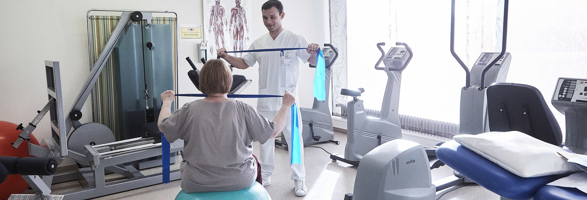 Ein Mitarbeiter der Abteilung für Physiotherapie in Kaiserslautern trainiert mit einer Patientin, die auf einem Ball sitzt