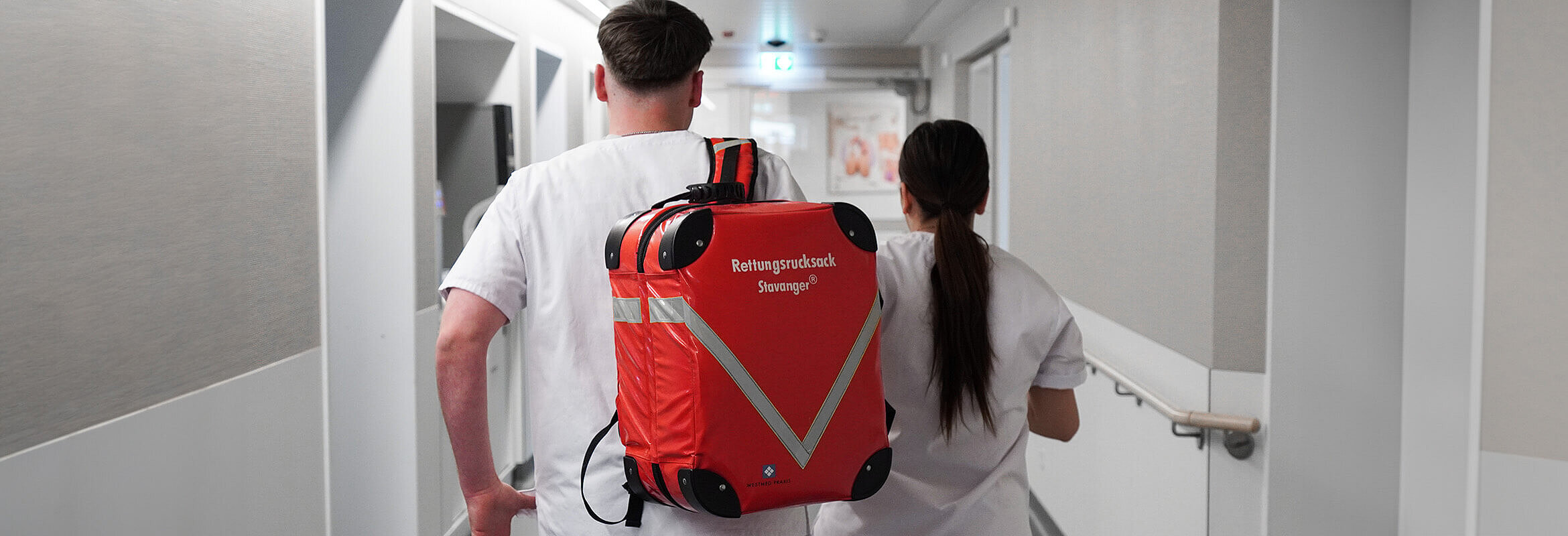 Auszubildende des Westpfalz-Klinikums sind mit einem Rettungsrucksack im Haus unterwegs.
